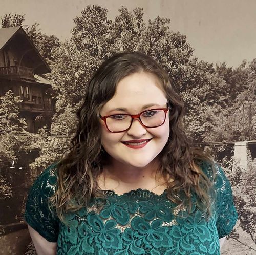 Samantha Hockmann in front of a picture of Tinker Swiss Cottage.